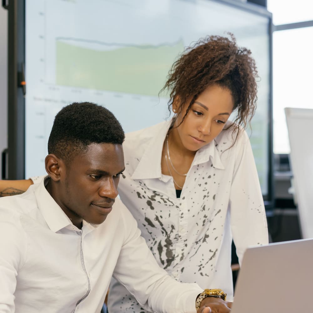 Two colleagues looking at a laptop together in an office.